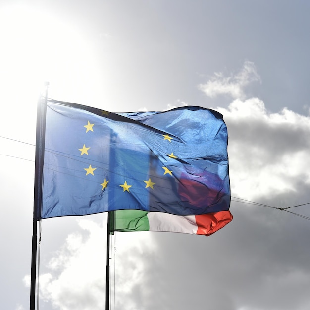 Bandiera europea e bandiera italiana che sventolano insieme in un cielo azzurro Rapporto tra l'Unione europea e i concetti dell'Italia