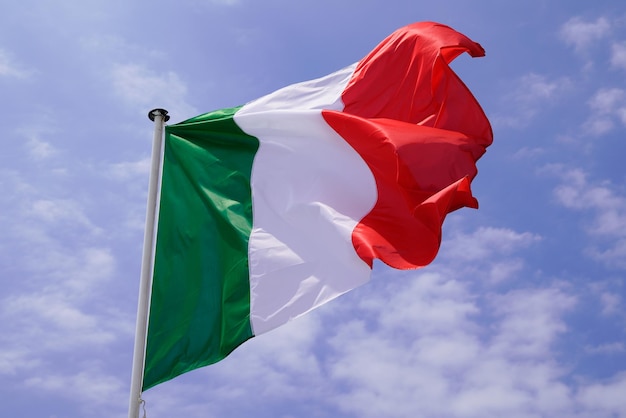 Bandiera italiana sulla stuoia nella nuvola di vento e cielo blu