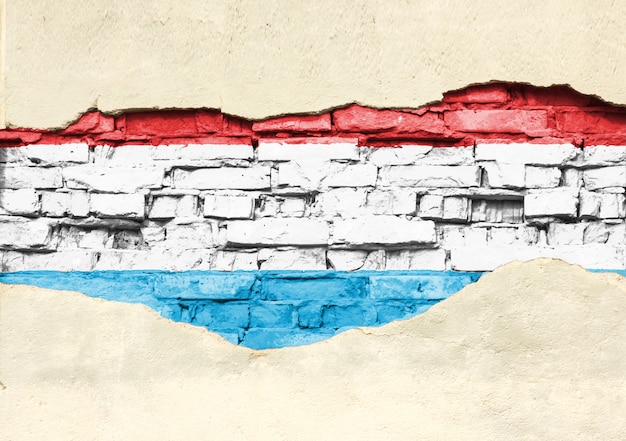 Bandiera nazionale del Lussemburgo su uno sfondo di mattoni. Muro di mattoni con intonaco parzialmente distrutto, sfondo o texture.
