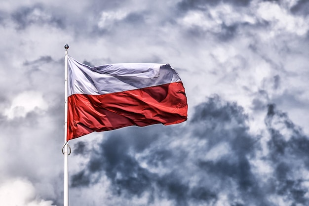 Bandiera nazionale della Polonia che sventola su uno sfondo scuro con cielo nuvoloso Effetto HDR