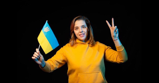 Bandiera nazionale ucraina Bella ragazza ucraina con bandiera del governo su un bastone nelle sue mani su sfondo nero Simbolo della statualità ucraina