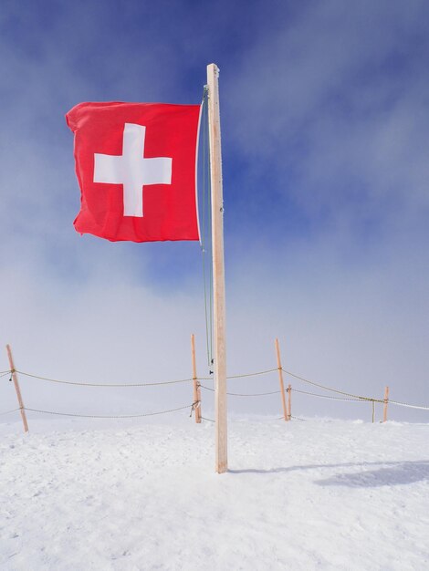 Bandiera rossa su terra coperta di neve contro il cielo