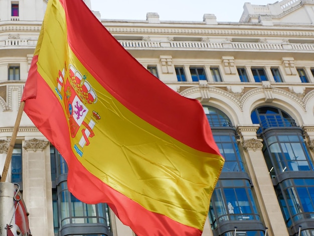 Bandiera spagnola che sventola contro gli edifici classici in Gran Via a Madrid Spagna