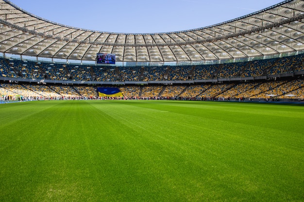 Bandiera ucraina e folla di persone allo stadio olimpico di calcio con panchine gialle e blu