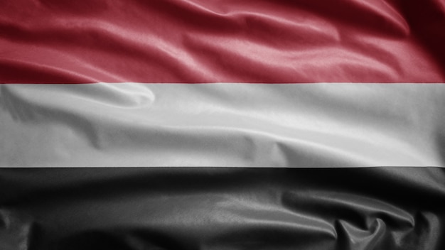 Bandiera yemenita che fluttua nel vento. Modello Yemen che soffia, seta morbida e liscia. Priorità bassa del guardiamarina di struttura del tessuto del panno.