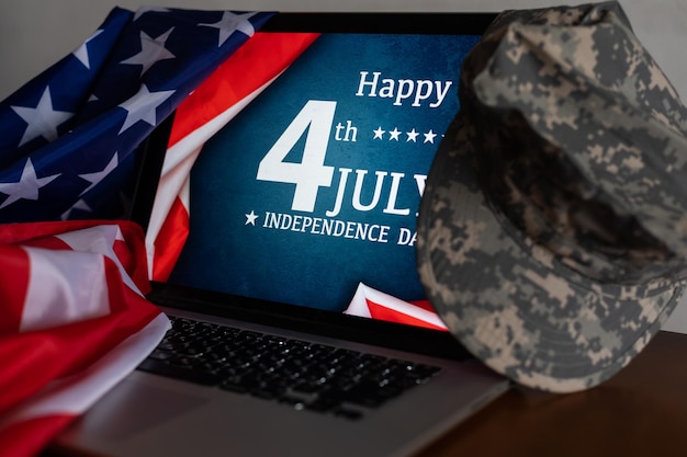 Bandiere americane con scritta Happy Independence Day sul computer portatile. berretto militare