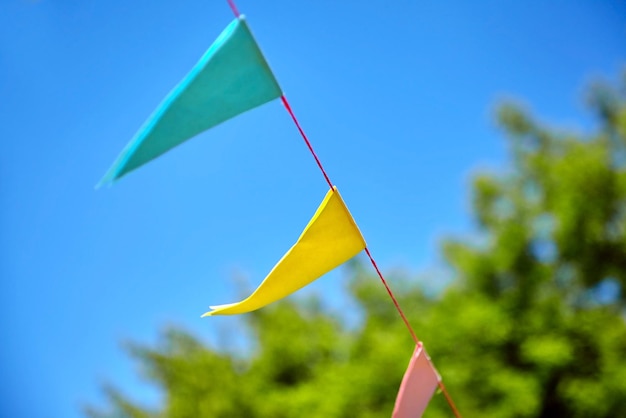Bandiere di festival di carta triangolari multicolori su sfondo blu cielo Atmosfera festosa per feste all'aperto