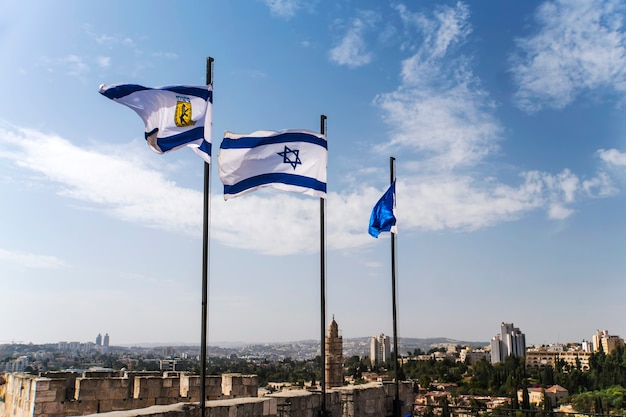 Bandiere di Israele e Gerusalemme sulle mura della città vecchia di Gerusalemme contro il cielo azzurro con nuvole bianche alla luce del sole. GERUSALEMME, ISRAELE. 24 ottobre 2018.