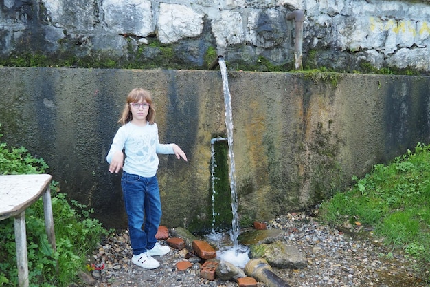 Banja Koviljaca Loznica Serbia Parco e foresta del Monte Guchevo Fonte di acqua minerale solforica e ferruginosa Ilidja Chesma Cesma Un getto d'acqua fuoriesce da un rubinetto in un muro di cemento Una ragazza