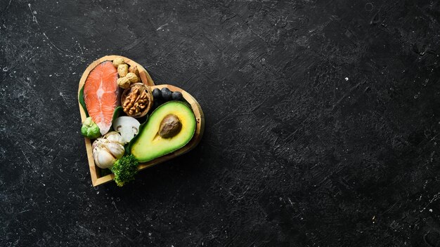 Banner alimentare Cibi sani a basso contenuto di carboidrati Cibo per la salute del cuore salmone avocado mirtilli broccoli e funghi Su uno sfondo di pietra nera Vista dall'alto