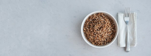 banner ciotola di grano saraceno su uno sfondo di cemento grigio nel concetto minimalista di una dieta equilibrata
