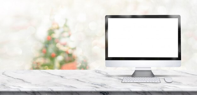 Banner di buon Natale, mock up desktop computer sul tavolo di marmo bianco con sfocatura albero di Natale