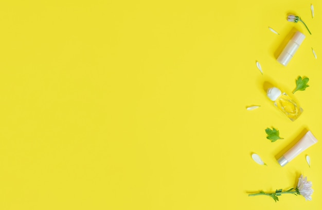 Banner di primavera con cosmetici e fiori su un giallo