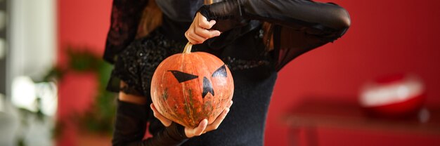 Banner di ragazza in maschera a casa in costume di halloween con zucca Jack o Laurent