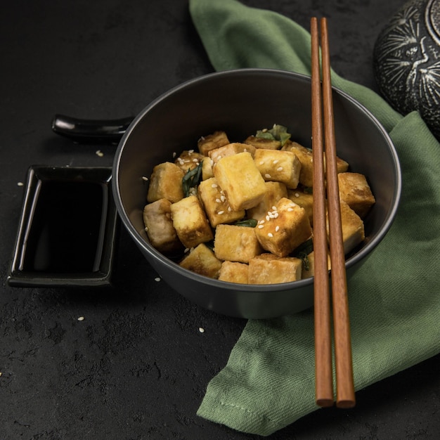 Banner di tofu fritto con prodotto di soia su sfondo nero e tovagliolo verde Proteine alternative Vegan