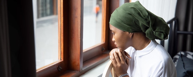 Banner di triste giovane donna africana malato di cancro che combatte con la malattia che indossa una sciarpa per la testa dopo aver subito un grave effetto collaterale di perdita di capelli a causa del concetto di chemioterapia di consapevolezza del cancro