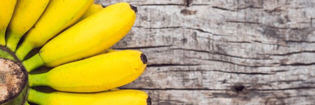 BANNER, mazzo di lungo formato di banane gialle organiche mature crude su fondo di legno