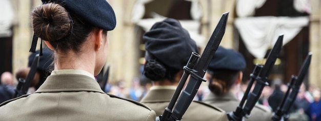 Banner orizzontale o intestazione con donne in uniforme in piedi durante la cerimonia militare a Bologna Italia In primo piano una donna vista da dietro con un fucile a baionetta