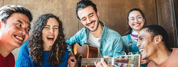 Banner orizzontale o intestazione con un gruppo di studenti multietnici alla moda che si divertono insieme nella sala ricreativa dell'università Giovani felici che si divertono suonando musica e ridendo insieme