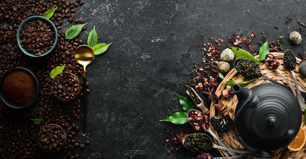 Banner per caffè e tè Chicchi di caffè aromatici e foglie di tè in tazze con teiera Bevande tradizionali su sfondo di pietra nera Vista dall'alto