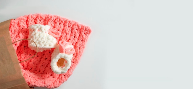 Banner regalo per un neonato Stivaletti bianchi fatti a mano per ragazze su un plaid rosa lavorato a maglia Un neonato alla moda Posizione piatta Vista dall'alto Posto per il testo