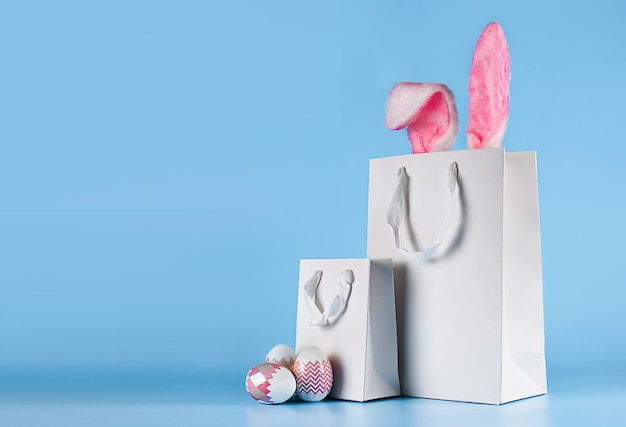 Banner su sfondo blu Il concetto di shopping online per gli acquisti e la vendita di Pasqua per le vacanze Borsa regalo con orecchie da coniglio e uova di Pasqua