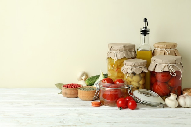 Barattoli di verdure sottaceto e ingredienti sul tavolo di legno bianco