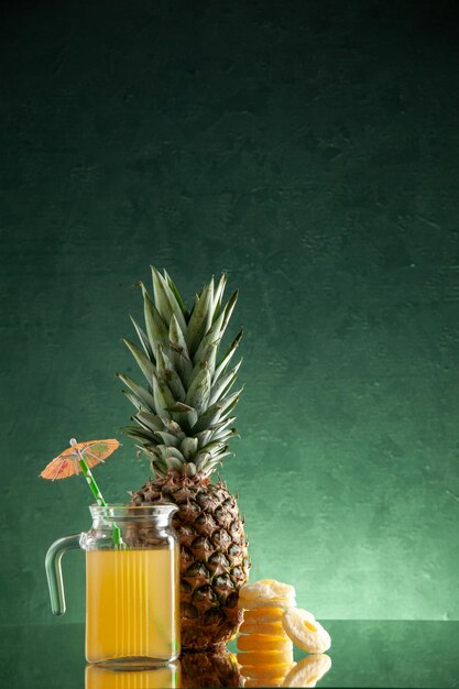 barattolo da cocktail in vetro vista frontale con succo e ombrellone ananas secco anelli ananas su sfondo verde