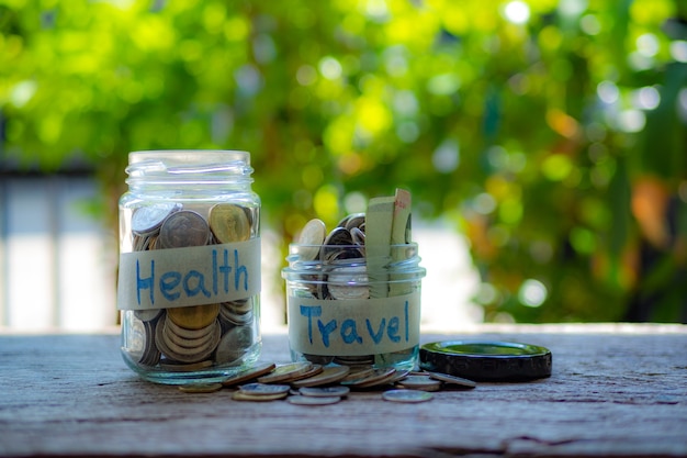 Barattolo dei soldi con le monete sul concetto di legno della tavola, di salute e di viaggio
