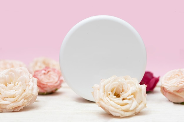 Barattolo di crema, mockup su uno sfondo rosa circondato da rose.