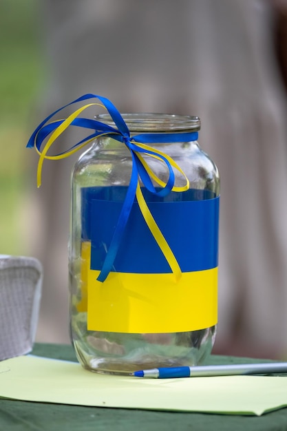 Barattolo di donazione. Evento di beneficenza. Aiuti all'Ucraina. Bandiera ucraina blu-gialla. Guerra in Ucraina.