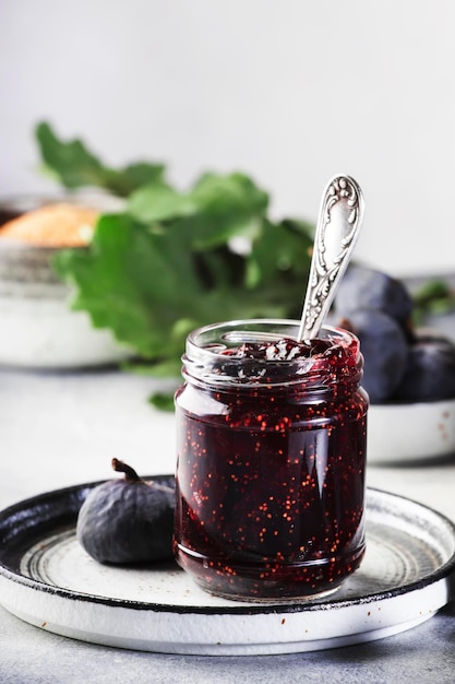 Barattolo di marmellata di fichi rossi dolci Fichi blu freschi Preparazioni fatte in casa e conserve Spazio per la copia dello sfondo del tavolo grigio