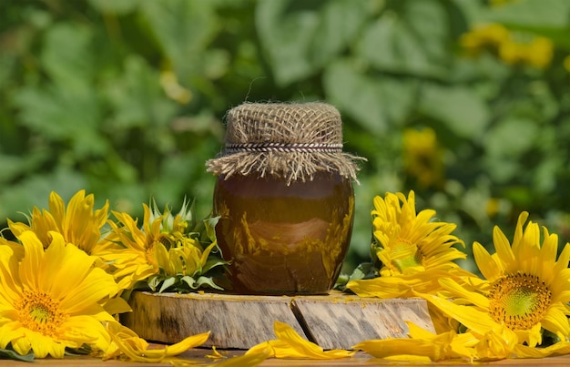 Barattolo di miele e girasoli su vecchio sfondo texture legno vintage retrò Barattolo di miele fresco nel campo dei fiori di campo