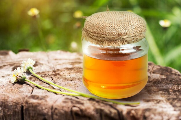 Barattolo di miele su un pavimento di legno nei campi di fiori con la freschezza della natura