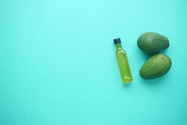 barattolo di olio e fetta di avocado su sfondo verde chiaro