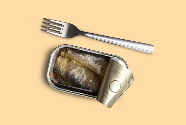 Barattolo di pesce aperto per preservare la sardina e forchetta d'argento isolata su uno sfondo giallo