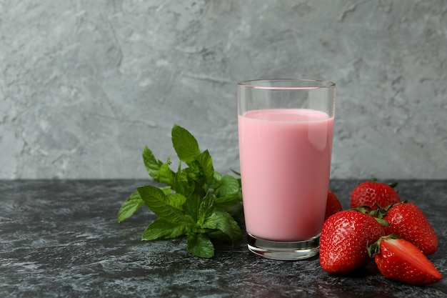 Barattolo di vetro di frappè alla fragola e ingredienti sul tavolo affumicato nero