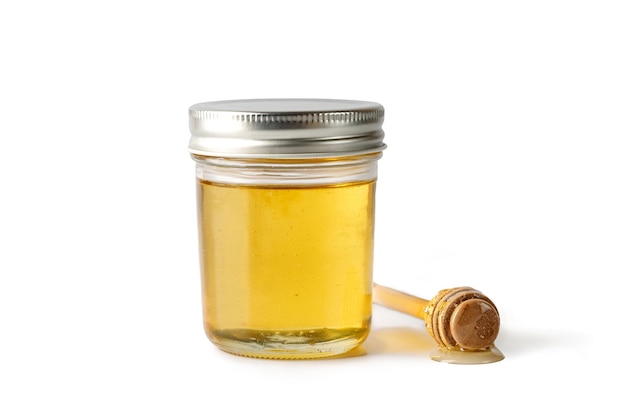 Barattolo di vetro di miele con coperchio in metallo drizzler mestolo di miele in legno isolato su uno sfondo bianco