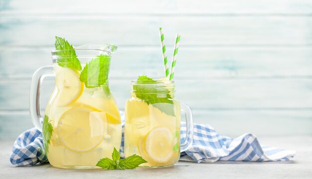 Barattolo di vetro e caraffa con limonata fatta in casa al limone e menta con spazio per la copia