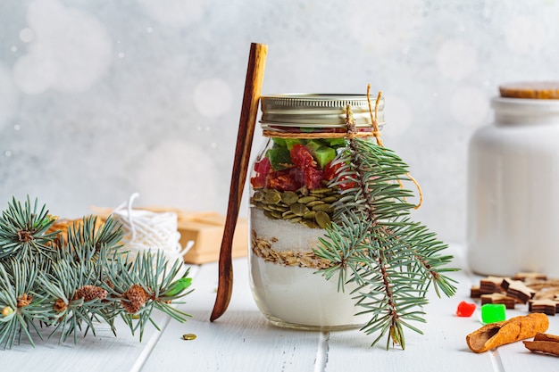 Barattolo per biscotti natalizi. Ingredienti secchi per cucinare i biscotti di Natale in un barattolo, sfondo bianco.