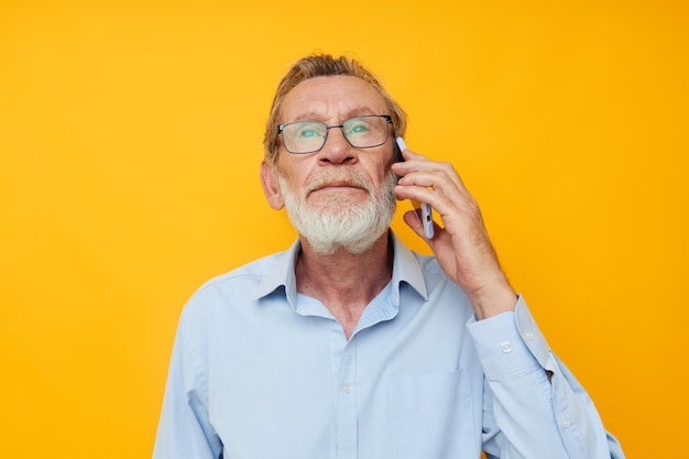 Barba grigia del vecchio con gli occhiali che parlano al telefono sullo sfondo isolato