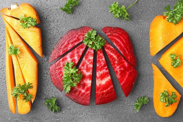 Barbabietola e carote affettate giovani fresche con prezzemolo su fondo grigio