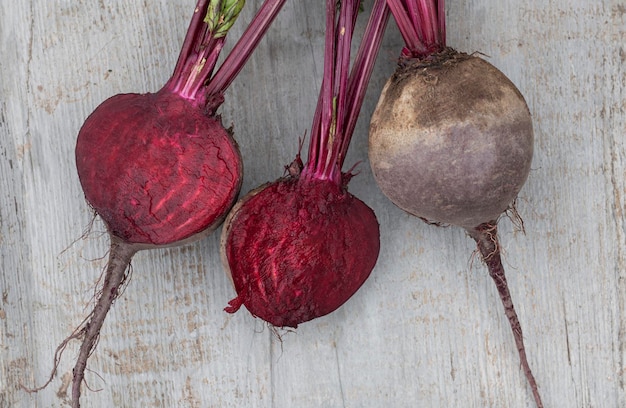 Barbabietole rosse lavate con cime tagliate a metà su una vista del piano di lavoro in legno