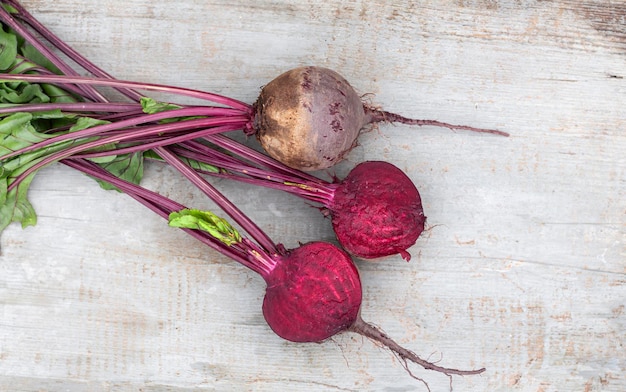 Barbabietole rosse lavate con cime tagliate a metà su una vista del piano di lavoro in legno