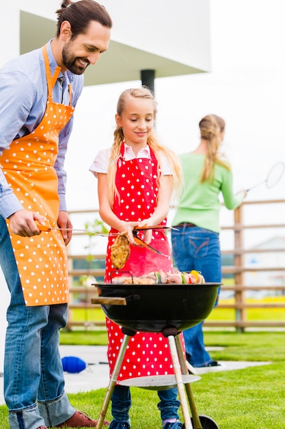 Barbecue della famiglia insieme nella casa del giardino