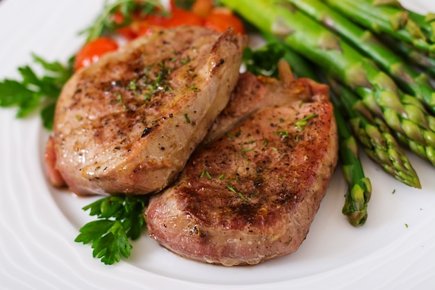 Barbecue di carne di manzo alla griglia con asparagi e pomodori.