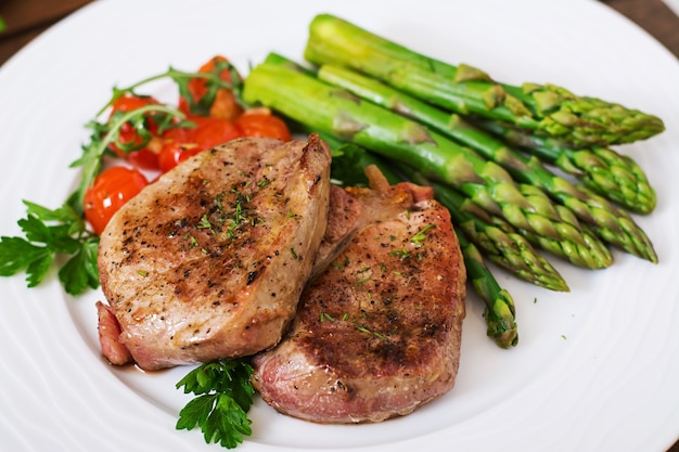 Barbecue di carne di manzo alla griglia con asparagi e pomodori.