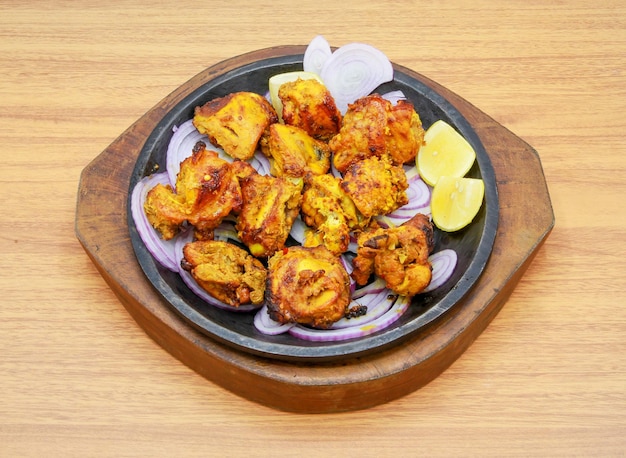 Barbecue piccante di pollo tikka boti kabab con limone e cipolla servito in un piatto isolato su sfondo grigio vista laterale del cibo indiano pakistani