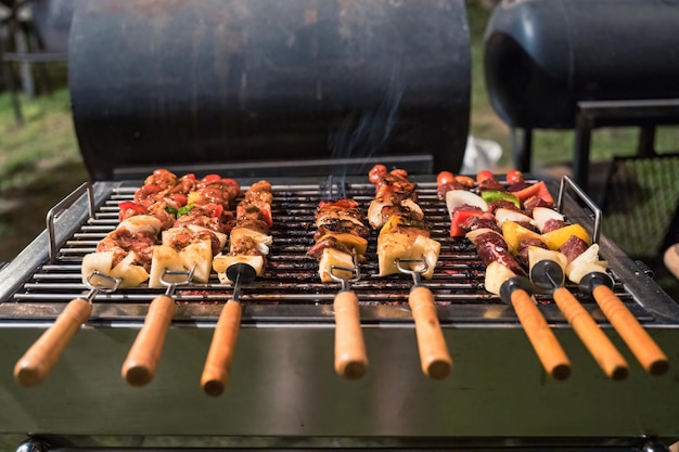 Barbecue spiedini di carne con grigliate di verdure sulla griglia del barbecue a carbone nel cortile