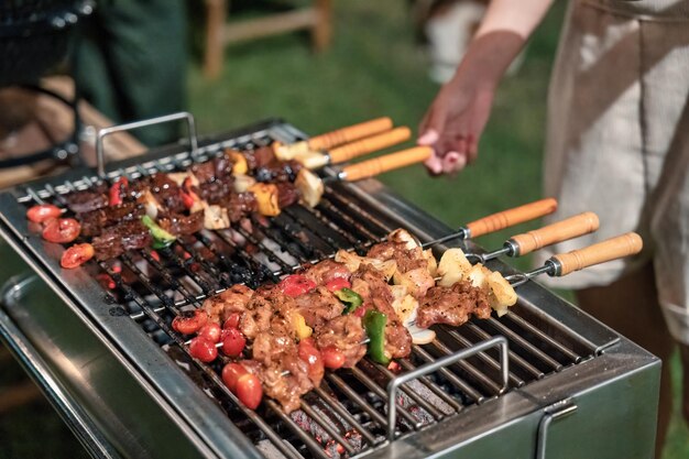 Barbecue spiedini di carne con grigliate di verdure sulla griglia del barbecue a carbone nel cortile